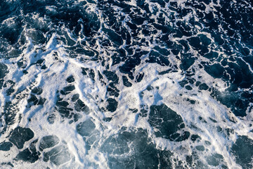 Top down aerial view of sea water surface. White foam waves texture as natural background.