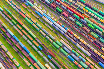 Cargo railway carriage. Aerial diagonally view from flying drone of colorful freight trains on the railway sort facility. Wagons with goods on railroad. Heavy industry, industrial concept scene.