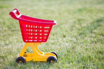 Bright plastic colorful shopping cart toy outdoors on sunny summer day.