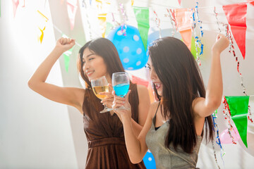 Party fun. Two attractive girls, cheerful best friends laughing out loud throwing colorful confetti while dancing and looking happy.