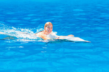 Happy little girl swimming with dolphins in Dolphinarium