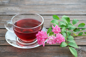 Cup of freshly made hot tea and pink roses on a old wooden table.