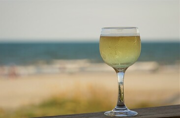 A glass of white wine  on wooden floor on the background of blurred beach and the Ocean, Summer at Myrtle beach in South Carolina USA.