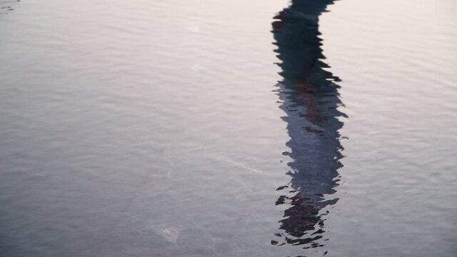 Lonely man walks reflected in the water. An atmosphere of sadness and loneliness. Slow motion
