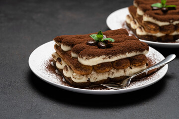 Two portions of Classic tiramisu dessert on ceramic plate on concrete background