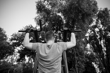 Guy training in outdoor gym on exercise equipment