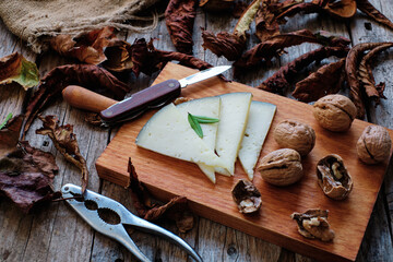 Slices of aged cheese and walnuts with rustic background
