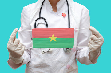 Epidemic in Burkina Faso. Young woman doctor in a medical coat or suit and gloves holds a medical...