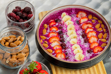 Tasty dragon fruit smoothie bowl with berries and toppings, healthy breakfast cereal