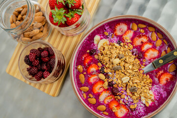 Tasty dragon fruit smoothie bowl with berries and toppings