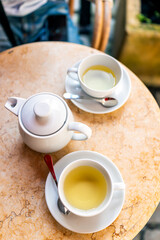 Closeup flat top lay of two white cups on plates of green tea in breakfast brunch outdoor cafe restaurant outside table with porcelain ceramic style teaware