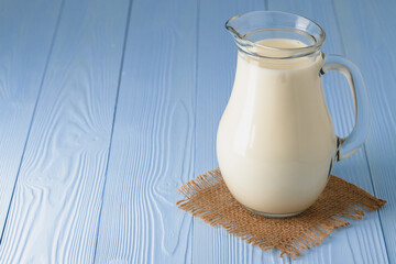Milk jug on blue wooden background close up