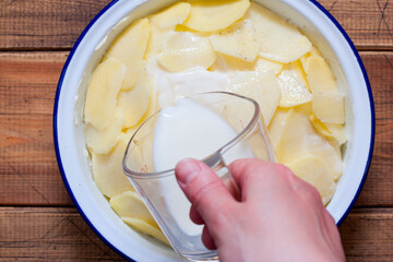 Cooking boulanger potato casserole step by step, step 5 - adding milk, top view, selective focus