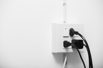 Electrical cord plug into electrical outlet on a wall. Electrical outlet and electrical switch with copy space.