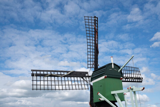 Green wooden windmill at a blue cloudy sky near the river Zaan in the Zaanse Schans, the Netherlands