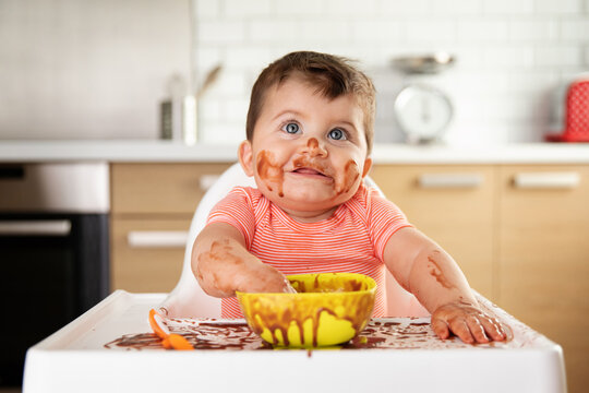 Cute smiling baby making mess while eating chocolate dessert