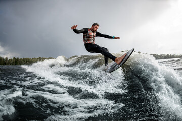 Handsome young man rides a wave with his surfboard. .