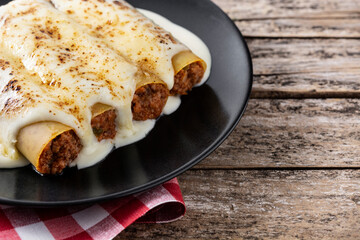 Delicious meat cannelloni pasta on wooden table	
