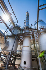 Sulphuric acid plant. Furnaces for sulfur burning for dioxide and smoking stack (factory chimney). Blue sky with sun background. Kzylorda region, Kazakhstan.