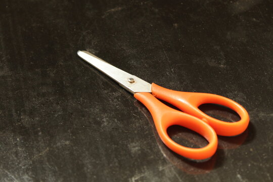 Scissors with a red handle on a black background