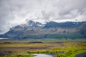 Landscape view on Skaftafell National Park, Iceland snow glacier with rocky cliffs snowcapped mountains and mist fog stormy clouds