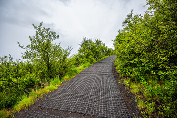 Skaftafell, Iceland green summer and steep trail path up hiking road covered from slippery rock wall and cloudy sky