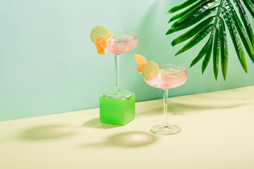 Alcohol Margarita cocktail with ice frappe, a slice of lime and orange zest on a tropical background with copyspace.