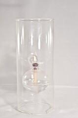 front view, close distance of a hand blown glass liquid candle holder with a lit wick