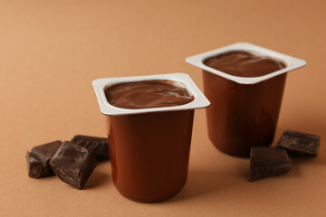 Plastics cups of chocolate yogurt on brown background