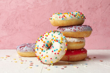 Tasty donuts on white table against pink background