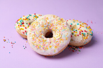 Three tasty donuts on violet background, close up