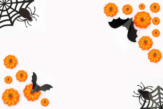 Frame halloween flat lay with pumpkins, spiders and bat on the white background