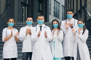 Corona Virus and Healthcare Concept. Medical staff from the hospital who are fighting coronavirus applaud back the people for their support. Group of doctors with face masks looking at camera