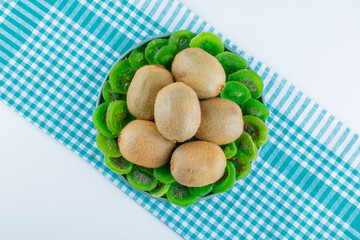 Fresh kiwi in a plate with dried kiwi flat lay on white and picnic cloth background