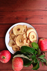 Homemade sun-dried organic apple slices, crispy apple chips, on an old rustic wooden table with fresh apple. Healthy snack. The concept is a healthy diet. Chips are part of a vegetarian diet.  