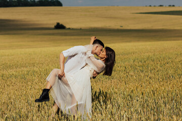 Young couple kissing in the wheat field. Stylish wedding photo session in rustic style. 