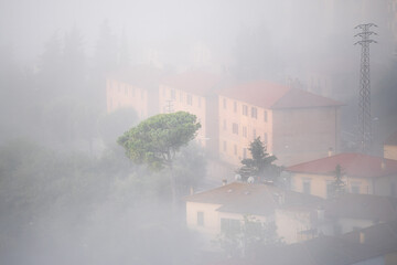 Chiusi Scalo town village houses fog sunrise closeup of rooftop building in Tuscany, Italy with soft clouds covering blanketing town cityscape roof