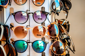 Closeup of many modern colorful sunglasses in outdoor market shop store rack in Rome, Italy outside...