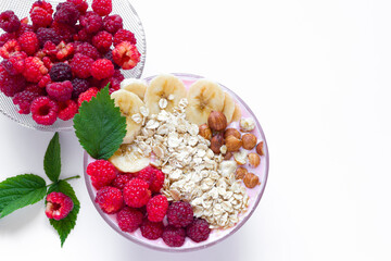 Healthy breakfast bowl: raspberry and fresh raspberry smoothie, banana, yogurt, nuts, oatmeal. Vegetarian concept, healthy food and diet. Top view, copy space.