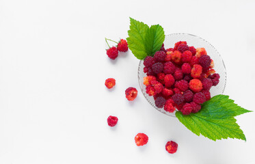 Red fresh raspberries on white isolated background. Bowl with natural ripe organic berries with green leaves, top view with copy space. Vegetarian concept.
