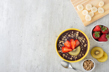 Brazilian typical acai bowl with fruits and muesli over wooden background. Top view with copy space
