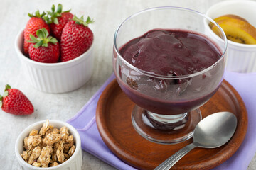 Brazilian typical acai bowl with fruits and muesli over wooden background