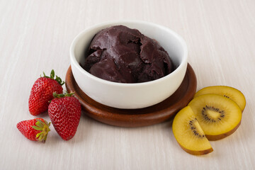 Brazilian typical acai bowl with fruits over wooden background