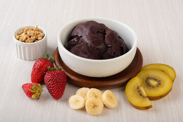 Brazilian typical acai bowl with fruits and muesli over wooden background