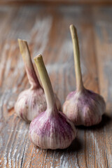 Three heads of garlic on a light wooden background close up