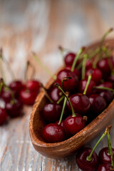Heap of ripe cherries in a wooden bowl, selective focus on a wooden table for a magazine