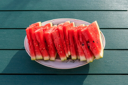 Sliced juicy red watermelon on a platter on a garden table against a garden background