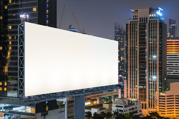 Obraz premium Blank white road billboard with Bangkok cityscape background at night time. Street advertising poster, mock up, 3D rendering. Side view. The concept of marketing communication to sell idea.
