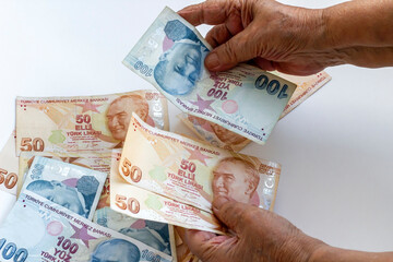 Old hand take Turkish money banknotes from black color her wallet on white table 
