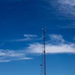 Obraz premium The tall metal tower with the clouds and the blue sky.